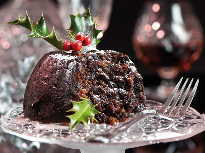 Half eaten Christmas pudding on a glass stand with fork
