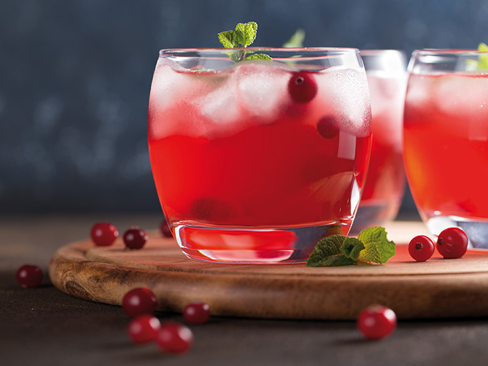 A cranberry cocktail with fresh mint on a wooden board